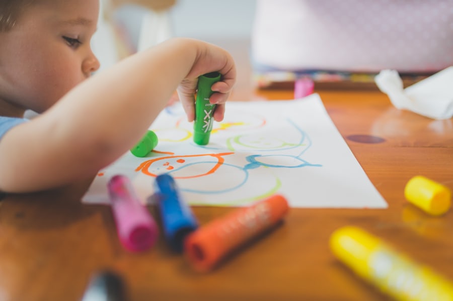 子どもがクレヨンを持って絵を描いている