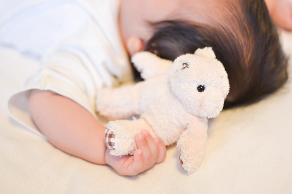 赤ちゃんがクマのぬいぐるみを握っている